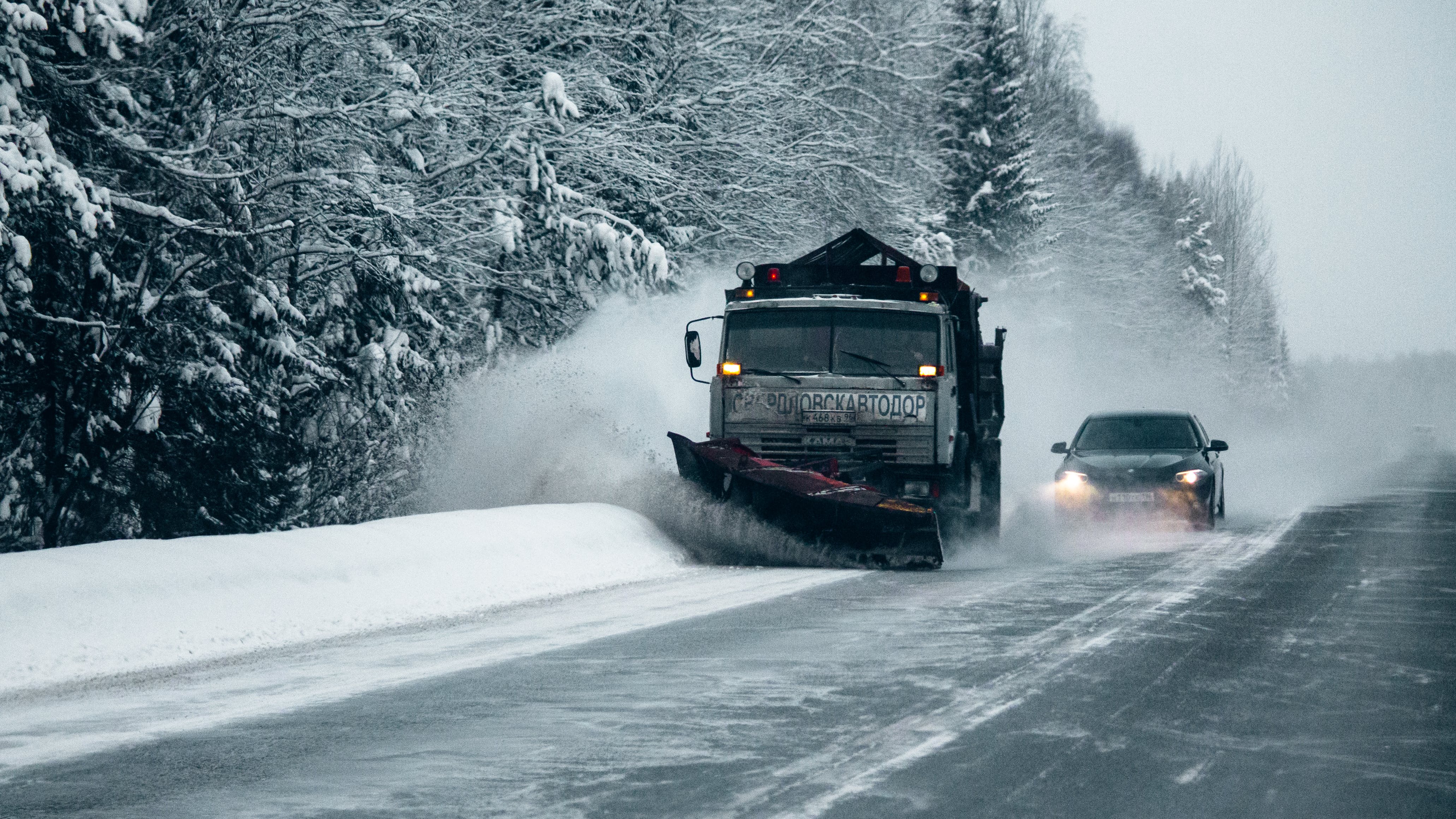 Snow plow with car behind it