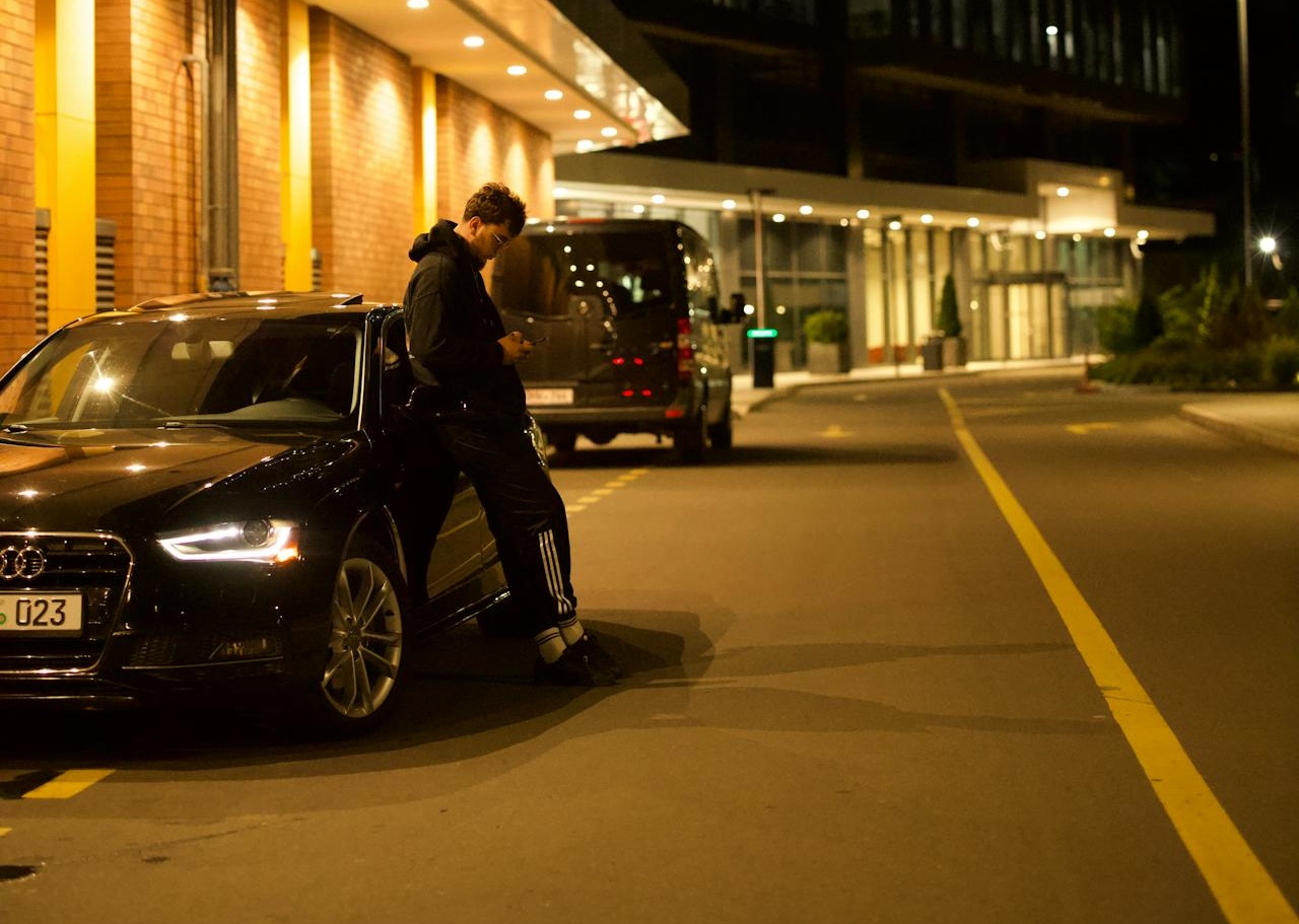 Man Leaning on a Car on a City Street