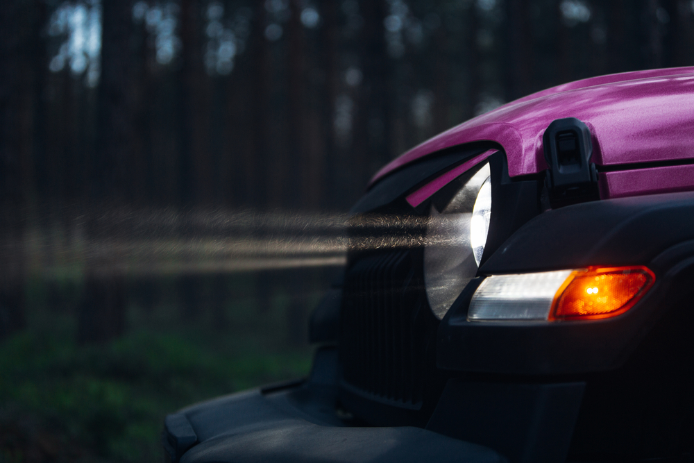 Modern car headlights with rays at the dark wood.