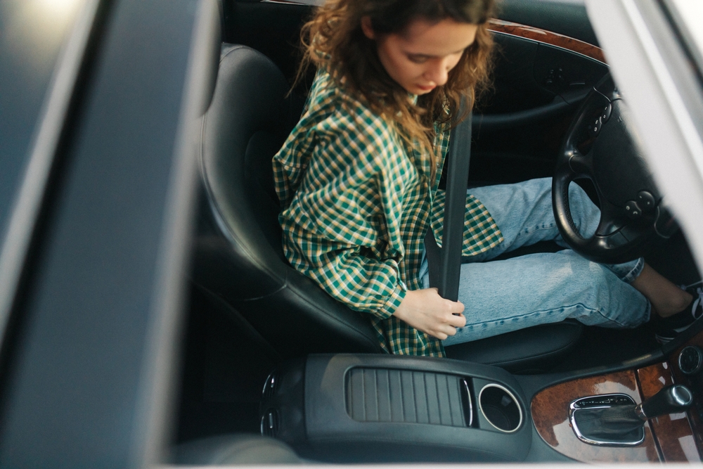 Young girl fastening her seat belt in the car.