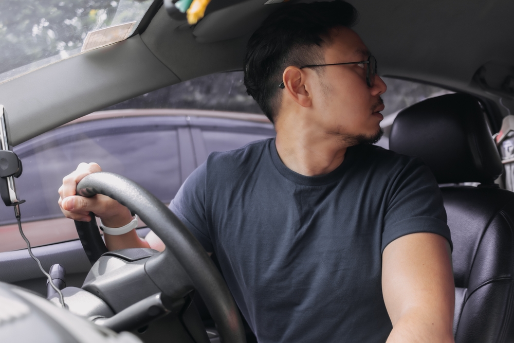 Asian Thai man looking at back while driving.