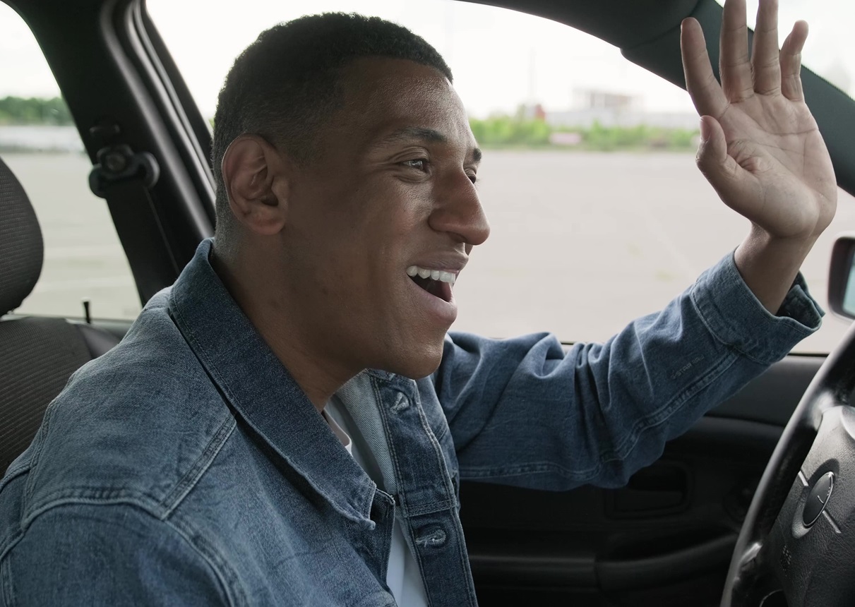 Happy male taxi driver waving by hand while driving.