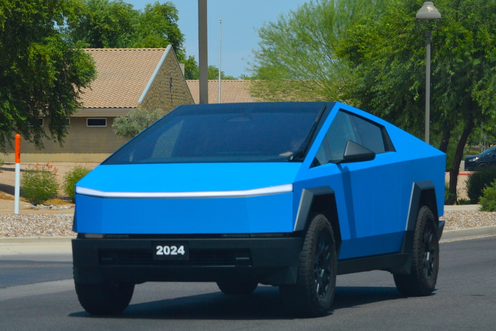 A bright blue colored, Tesla CyberTruck all electric model, driving on a city street.
