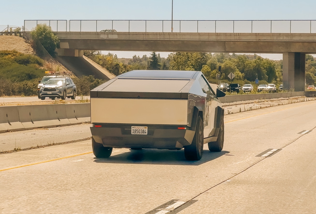 Tesla Cybertruck drives on a busy California highway under a clear blue sky - 2024