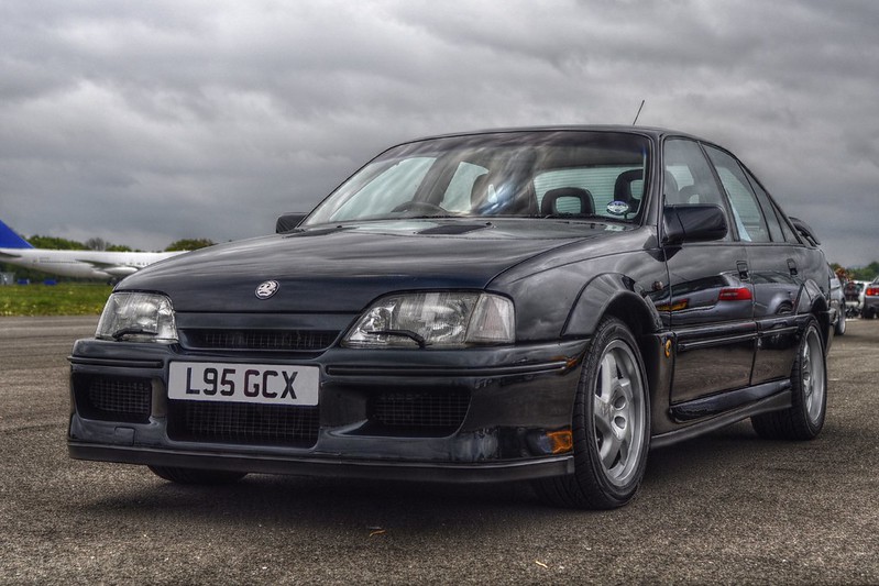 A close-up photo of a Black 1990 Lotus Carlton car parked in a parking lot