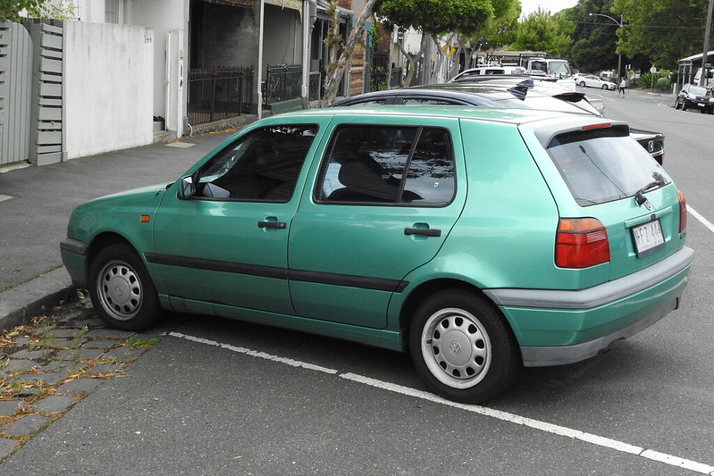 A close-up photo of a Green 1992 Volkswagen Golf MK3 car parked in a parking lot