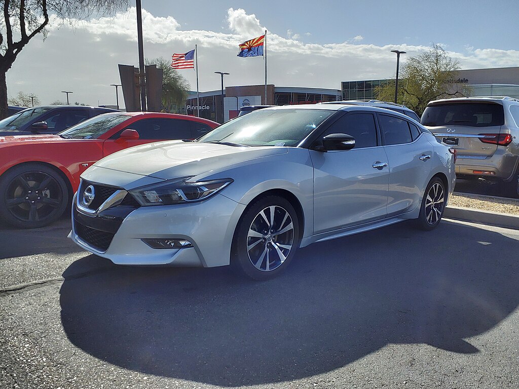 A close-up photo of a Silver Nissan Maxima car parked in a parking lot