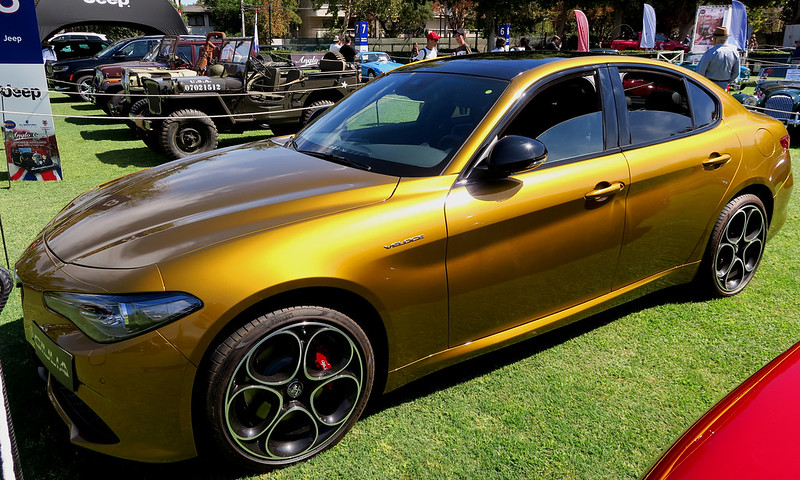 A close-up photo of a Golden Alfa Romeo Giulia car on display at an exhibition