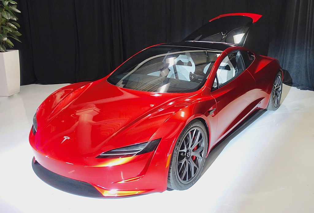 A close-up photo of a Red Tesla Roadster car on display at an exhibition