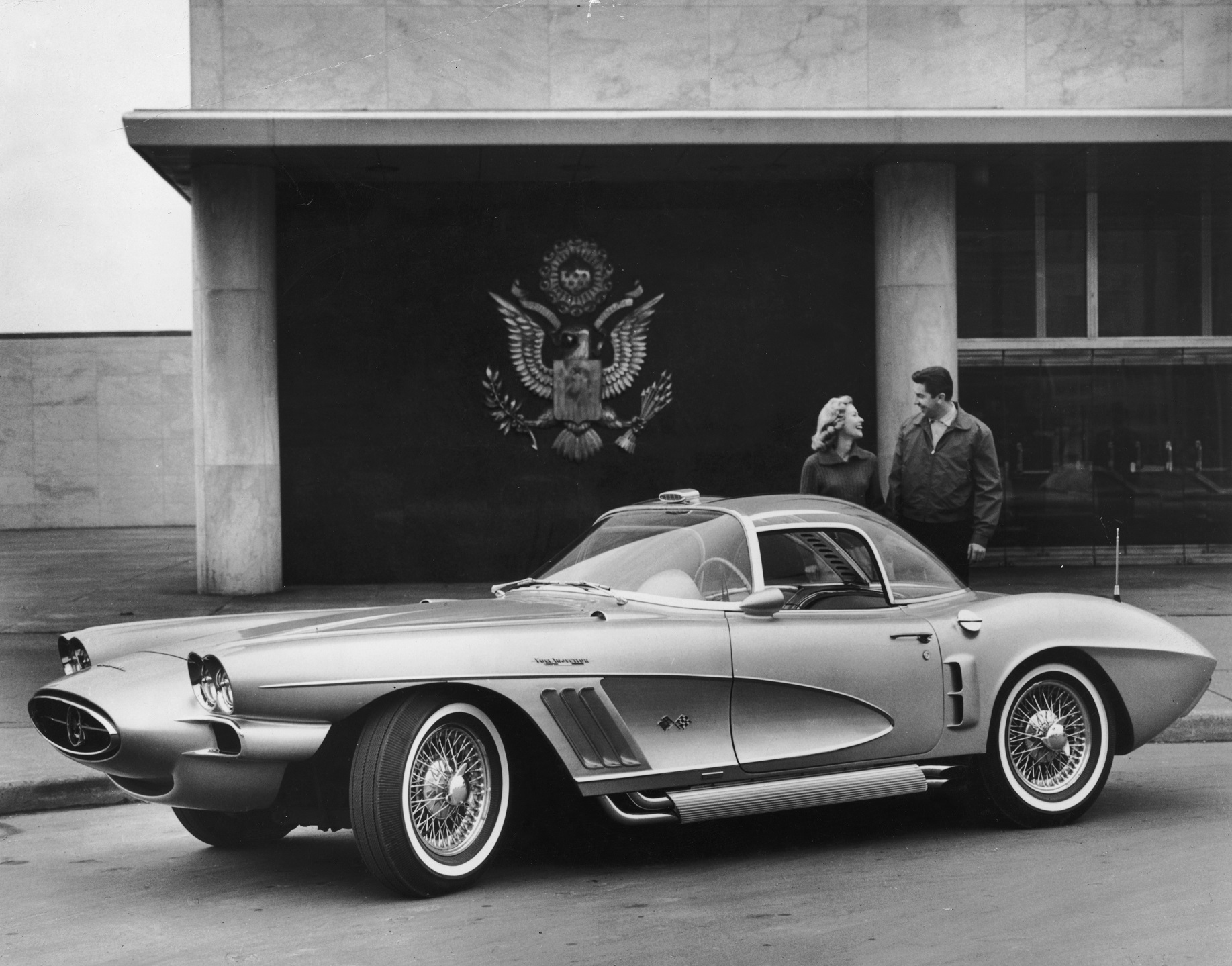 Promotional image of a couple laughing while posing behind an XP-700 1958 Corvette by Chevrolet.