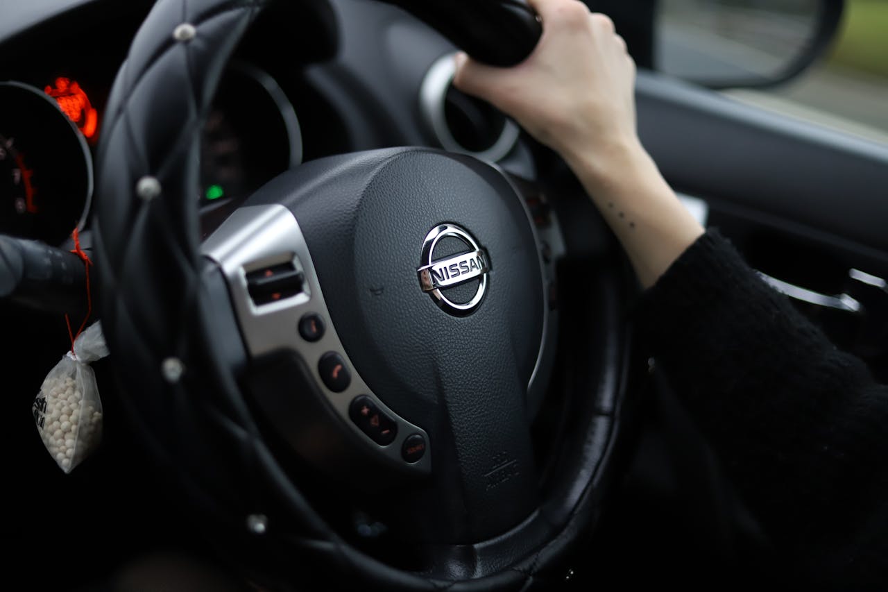 Hand Holding Nissan Car Steering Wheel