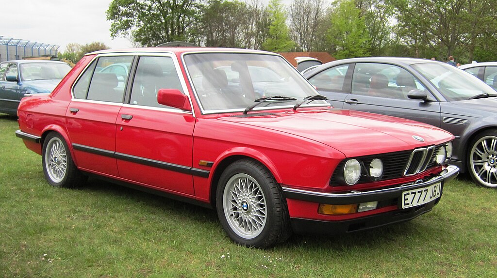 Close Up Photo of Red 1988 BMW M5 parked on grass