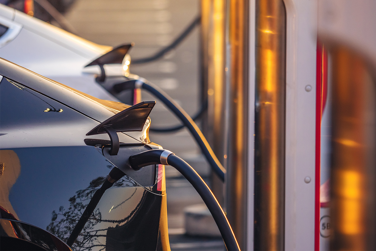 Electric cars charging at charging station outdoors at sunset.