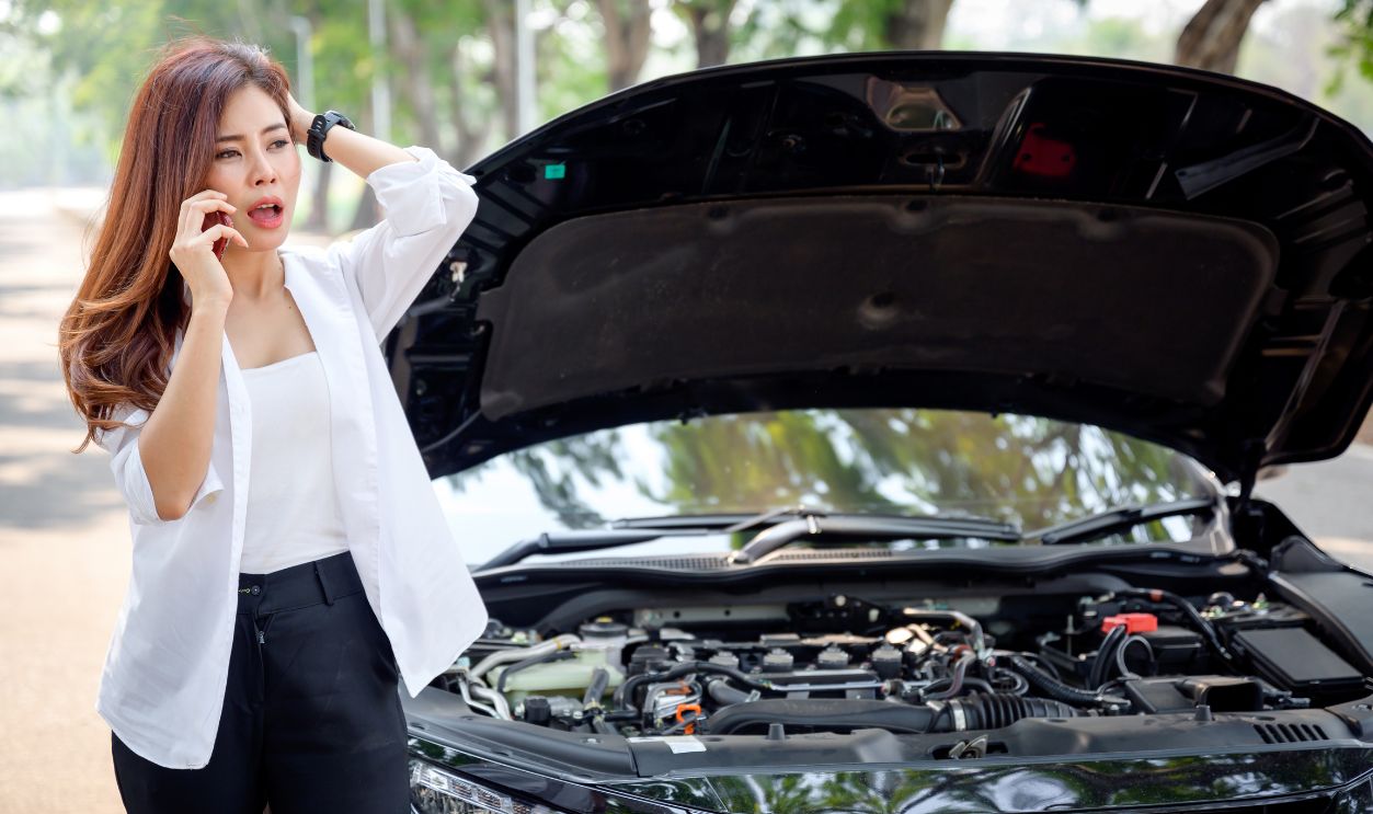 Asian woman opens the bonnet of a car