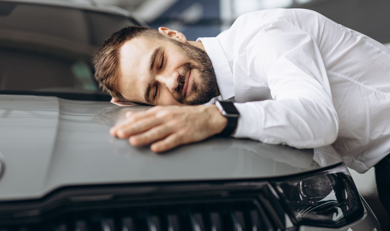 Man hugging his new car in car showroom