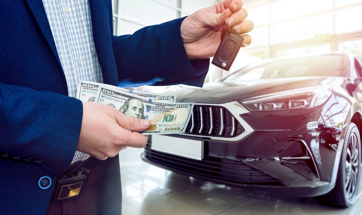 Businessman holding dollar bills in car showroom