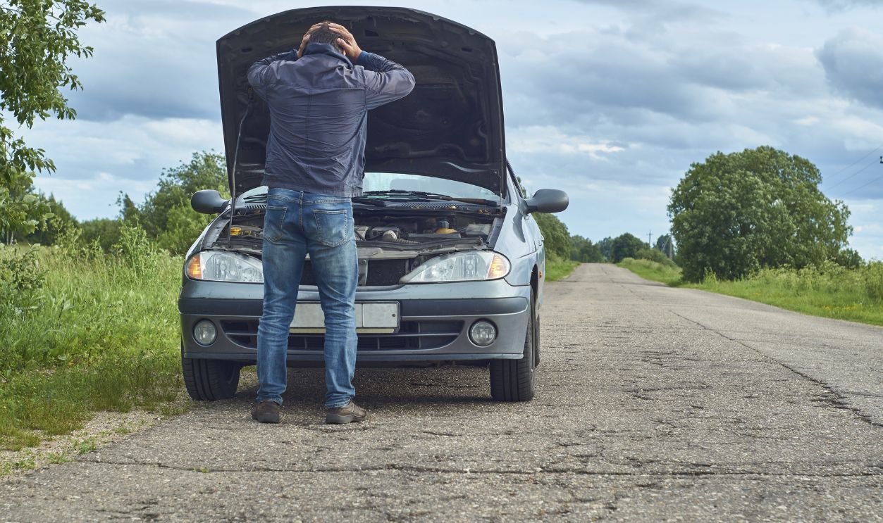 Worried man holding his head by hands standing near his old broken car