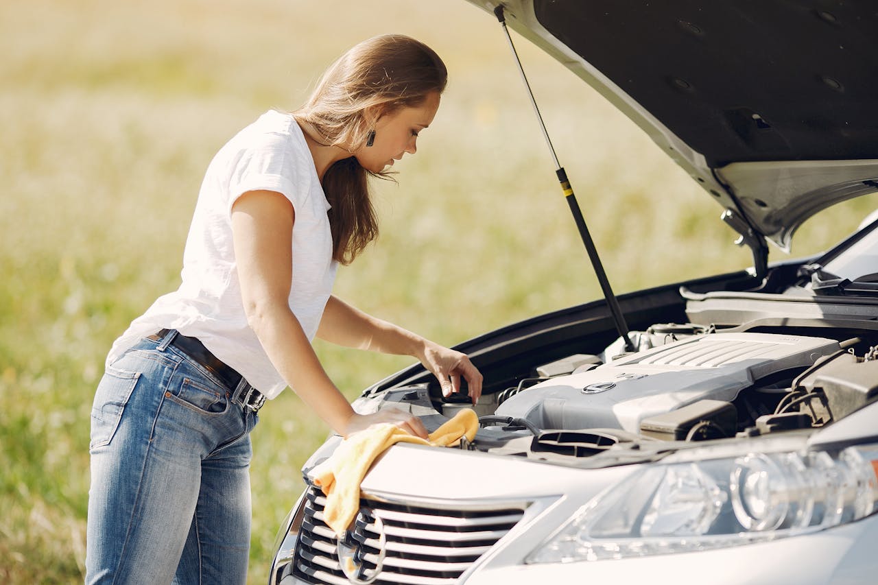 Troubled young woman near broken automobile in countryside