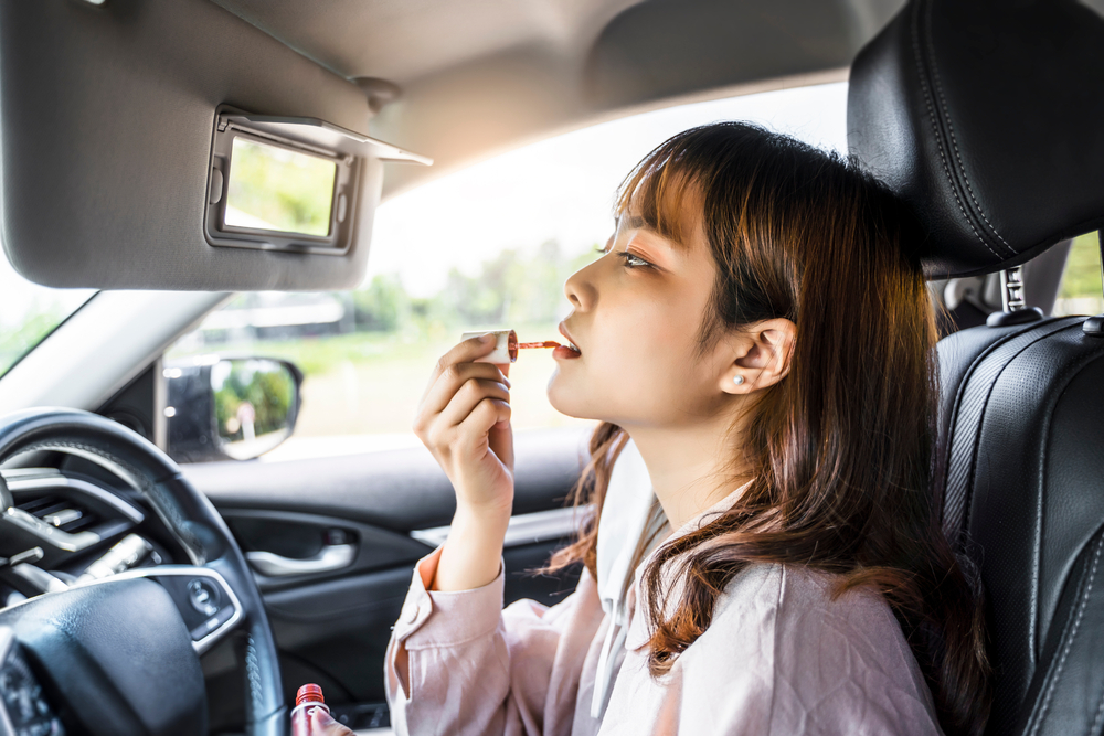 Woman driving in car , doing makeup