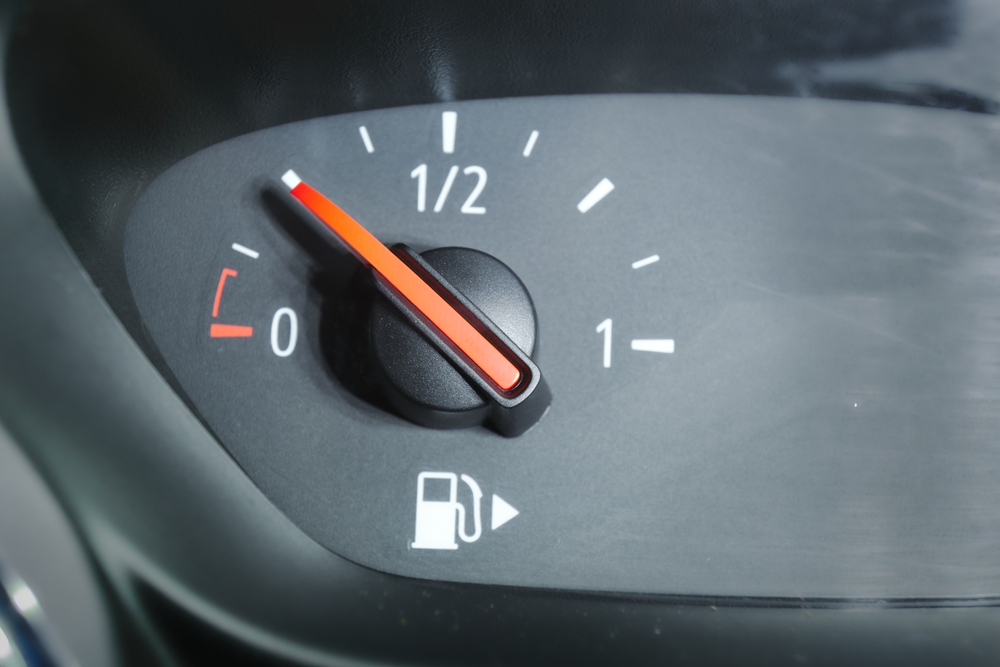 A close up of a fuel gauge showing a quarter full fuel tank in a car, gasoline consumption