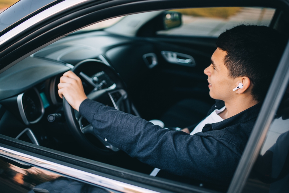 Man with wireless headphones driving a car.