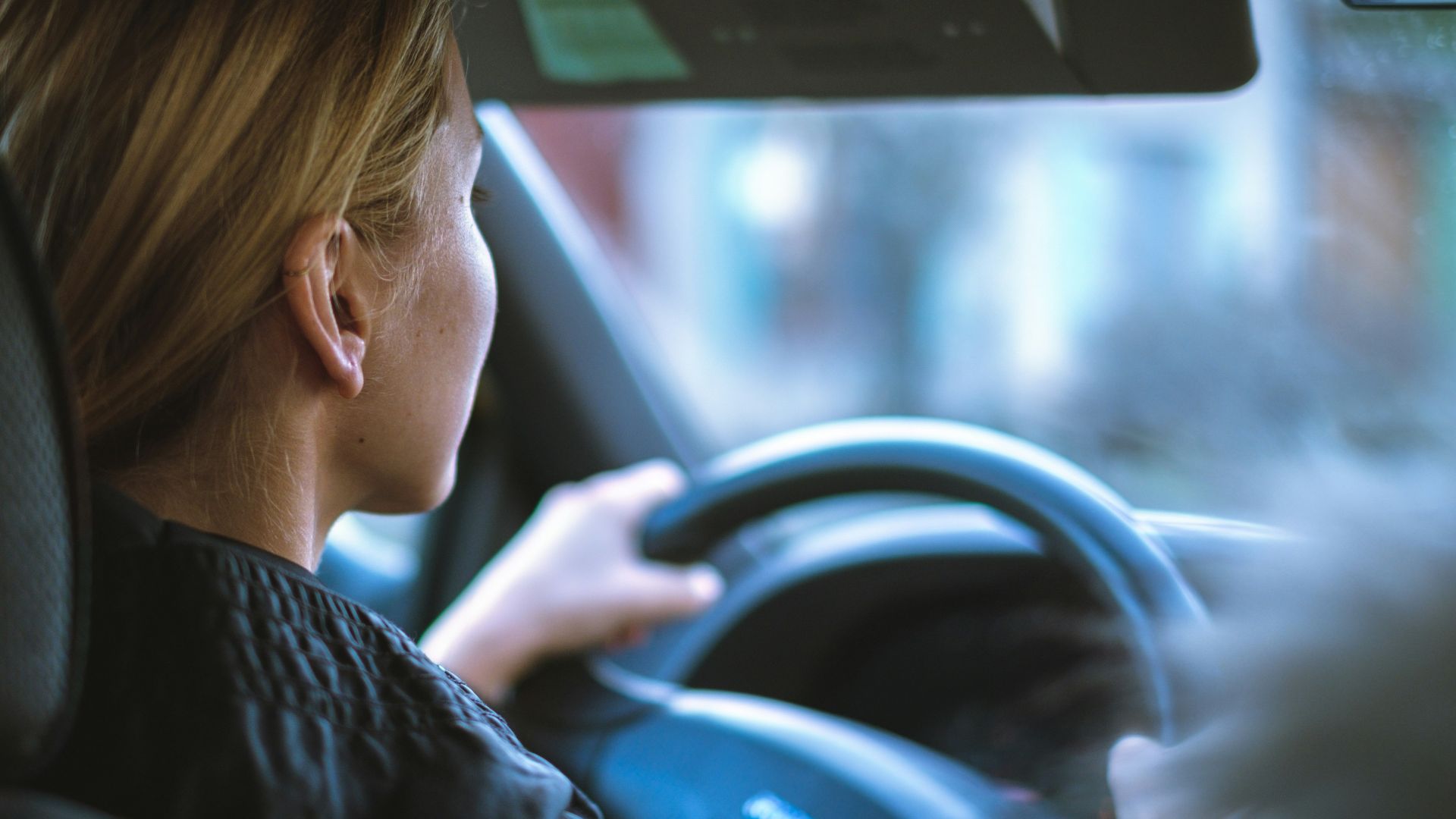a woman sitting in a car with a steering wheel