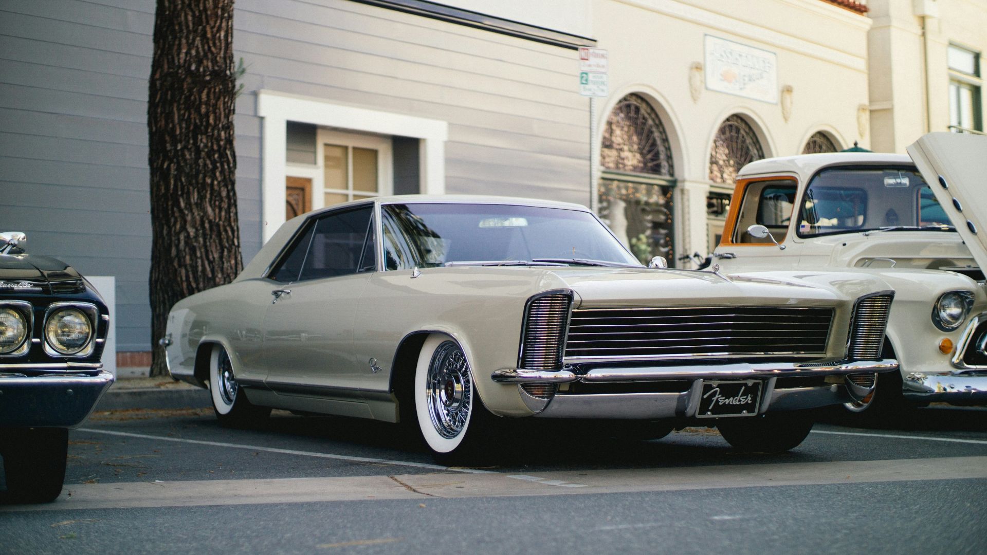 white coupe parked near tree and building
