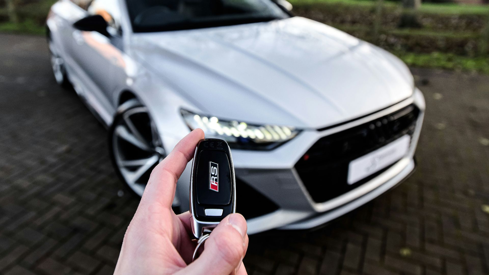 a person holding a car key in front of a silver car