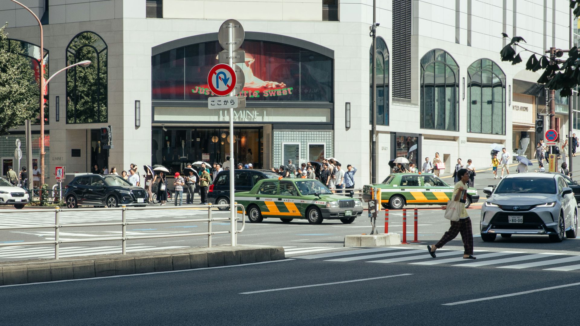 People cross a busy city street with vehicles.