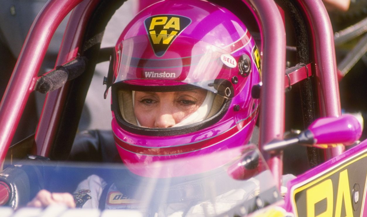 Shirley Muldowney sit in her race car at an NHRA Drag Racing event.
