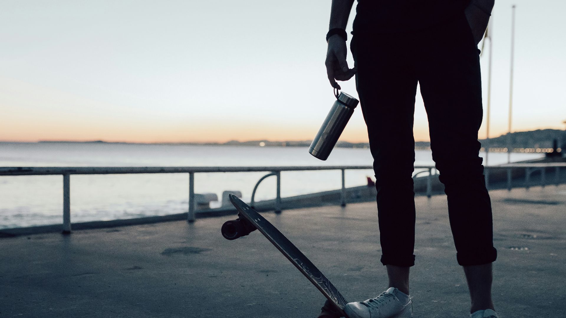 man in black jacket and pants holding skateboard