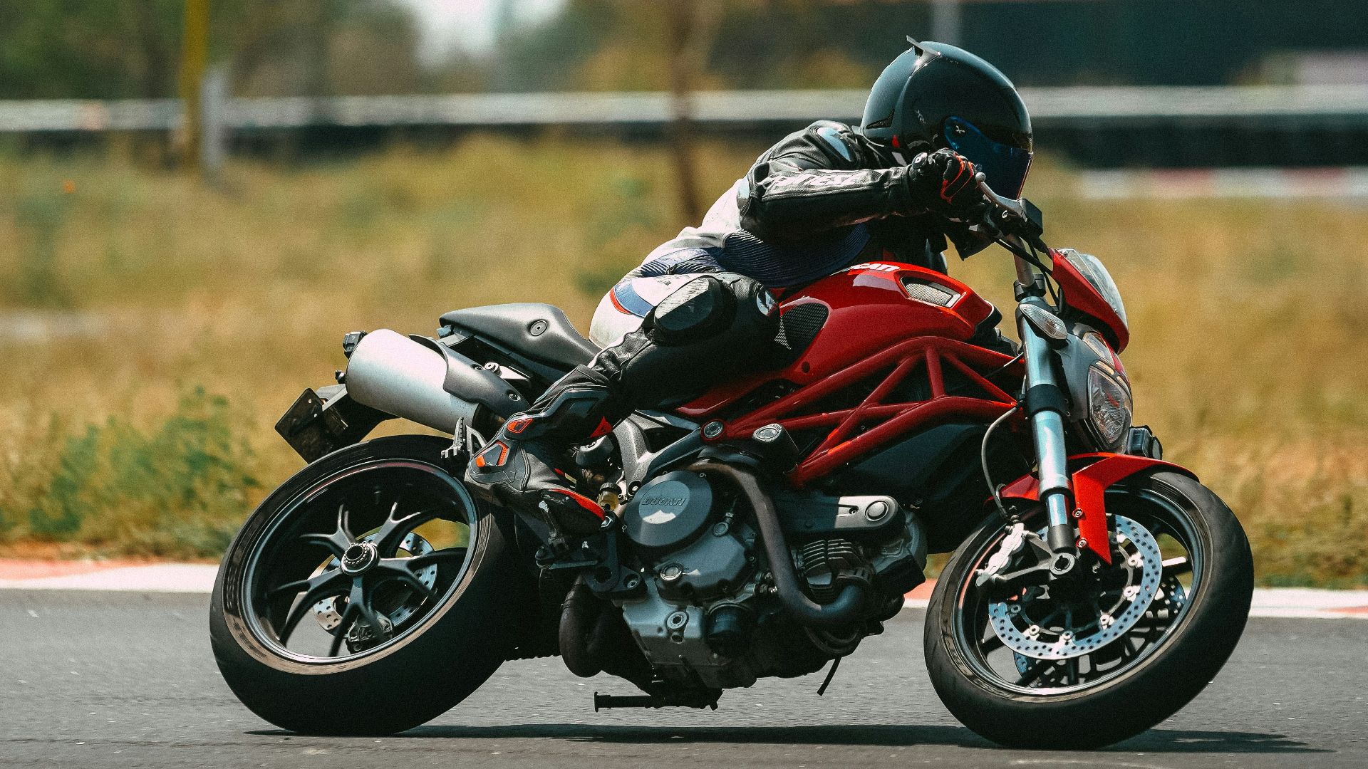 man in orange and black motorcycle suit riding motorcycle on road during daytime