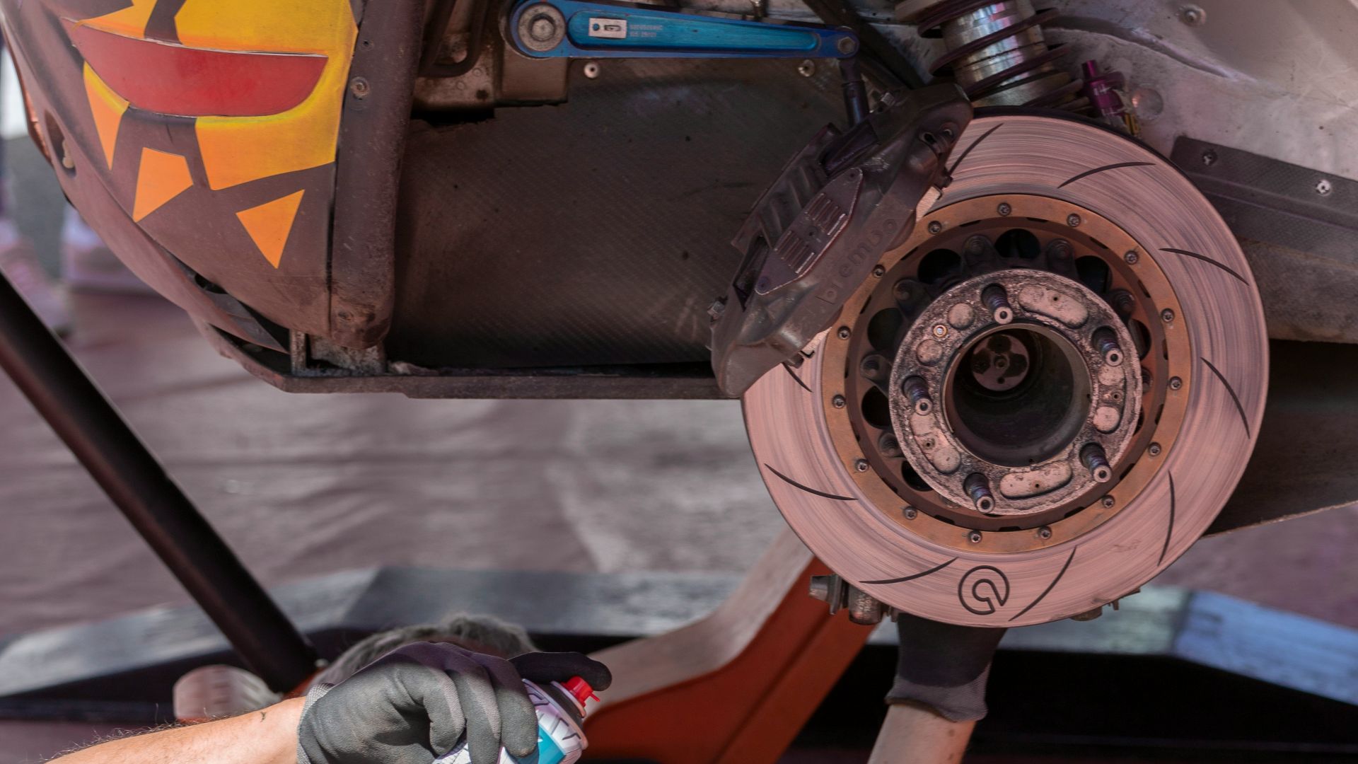 man fixing vehicle while holding spray can