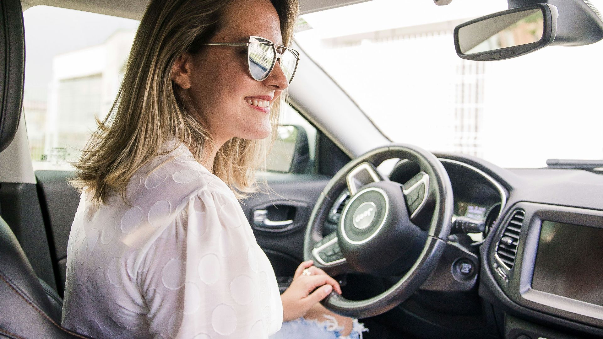 woman in white long sleeve shirt driving car