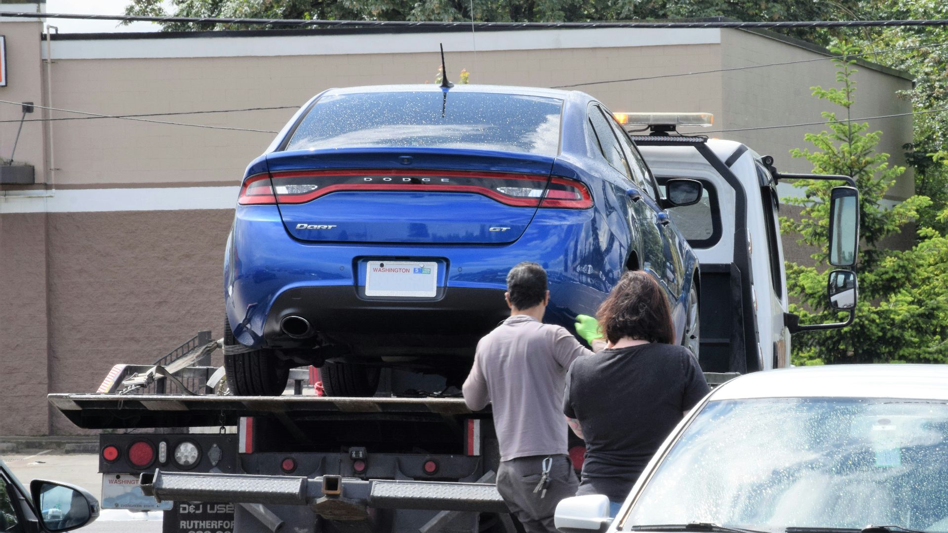 a blue car being loaded onto a flatbed truck