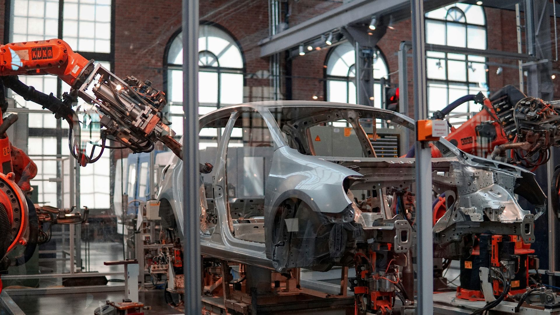 gray vehicle being fixed inside factory using robot machines