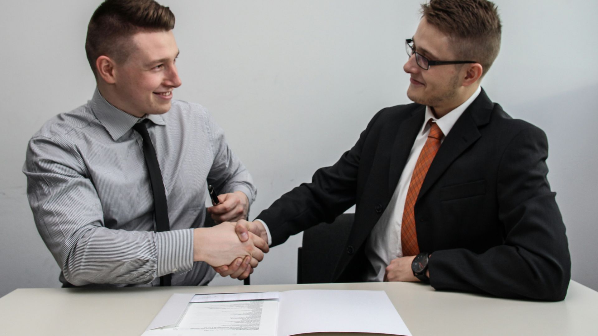 two men facing each other while shake hands and smiling