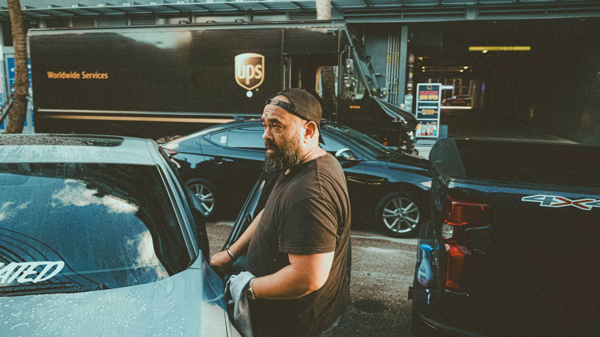 a man standing next to a parked car in a parking lot