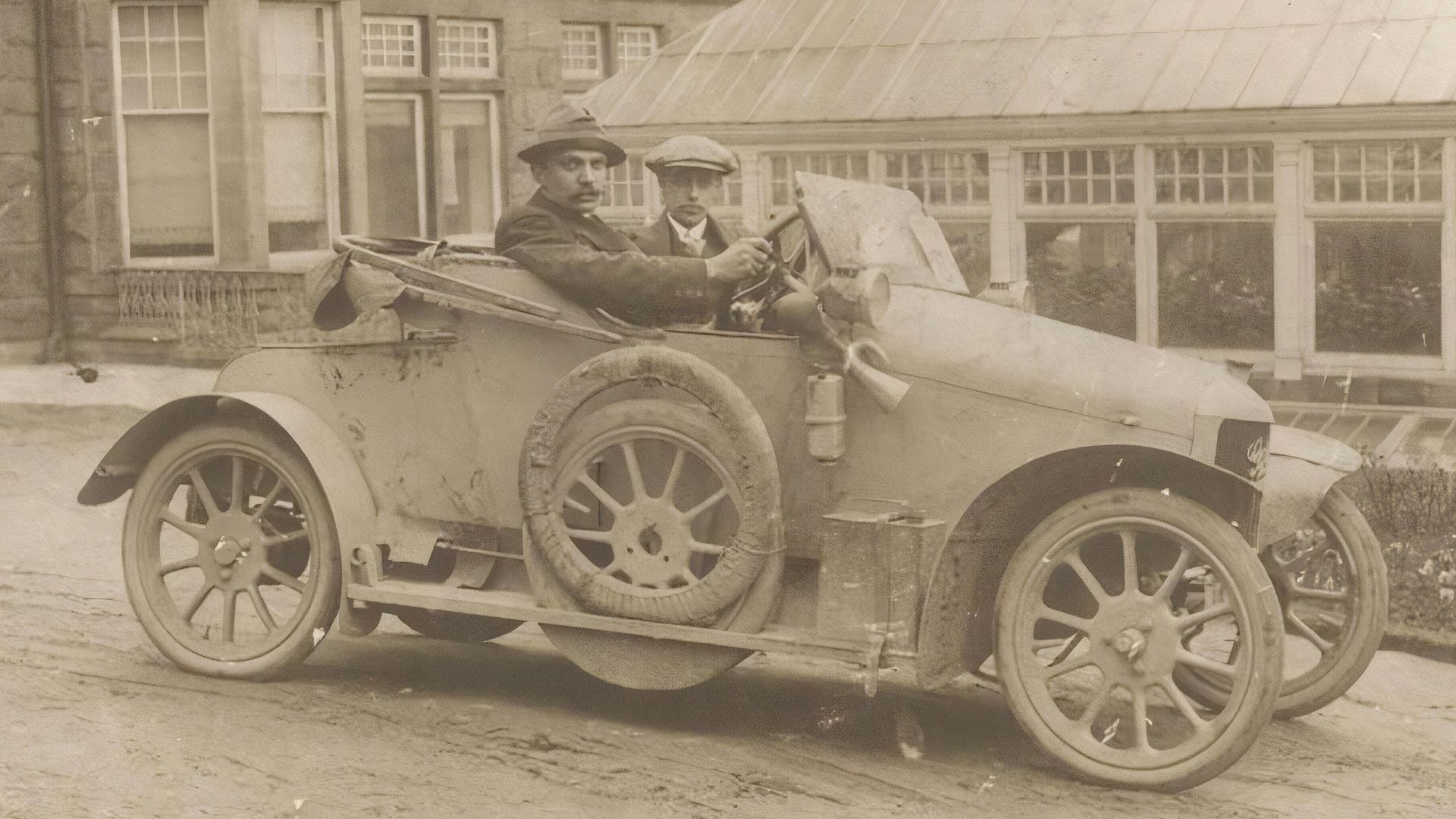 an old photo of two men in an old car