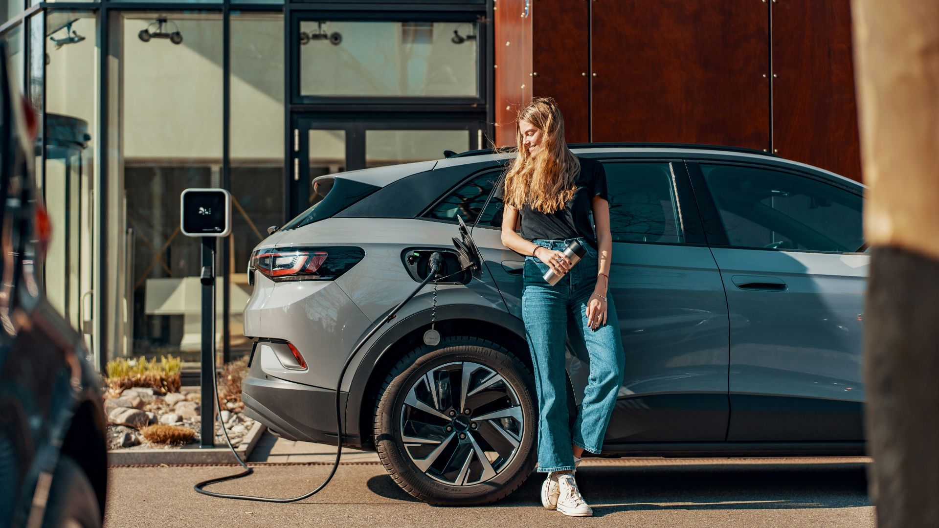 a woman standing next to a blue car