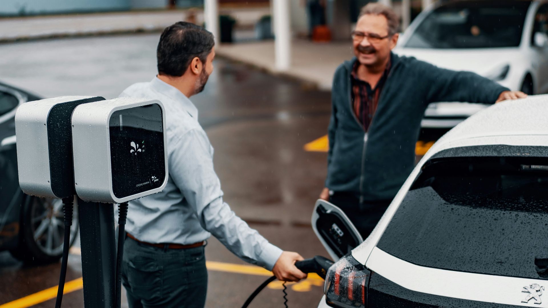 a couple of men standing next to a white car