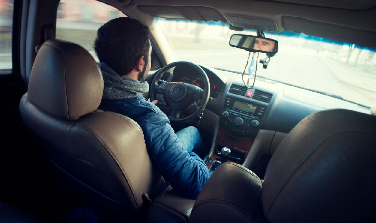 A man wearing a blue jacket sitting inside car