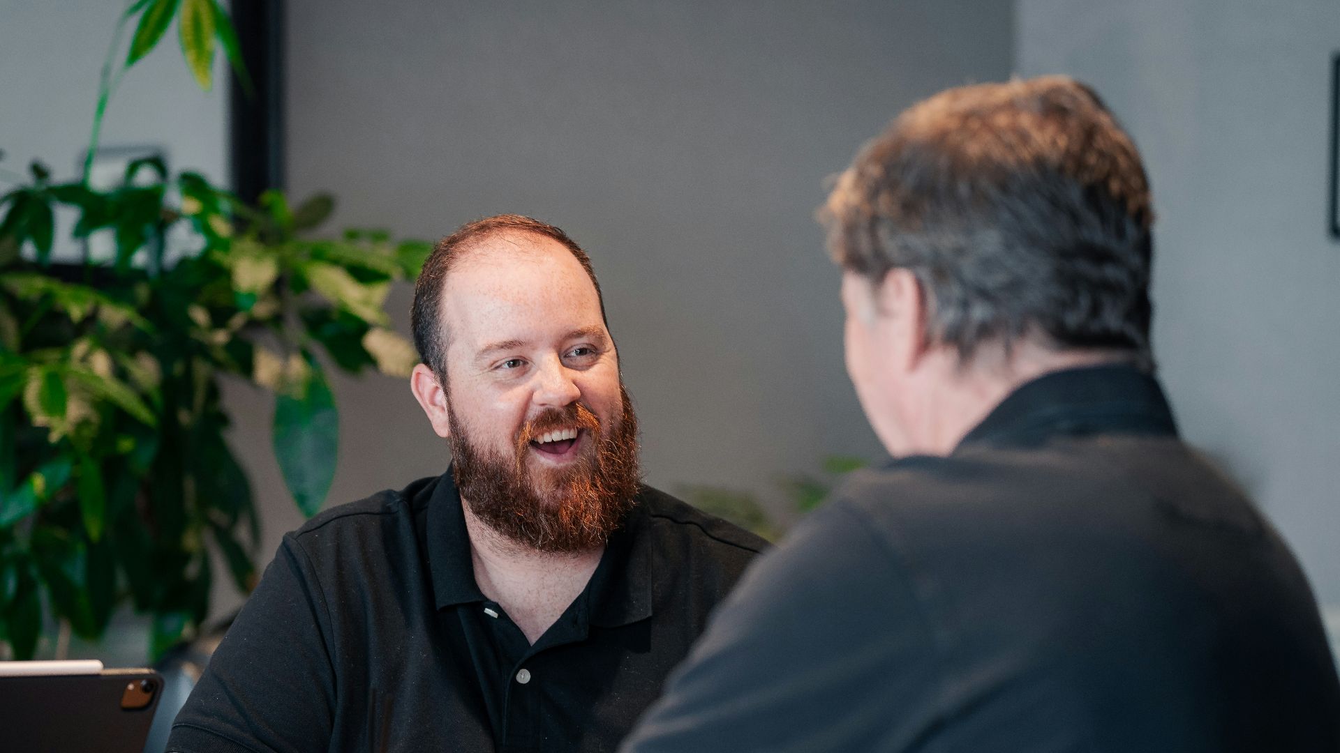two men sitting at a table talking to each other