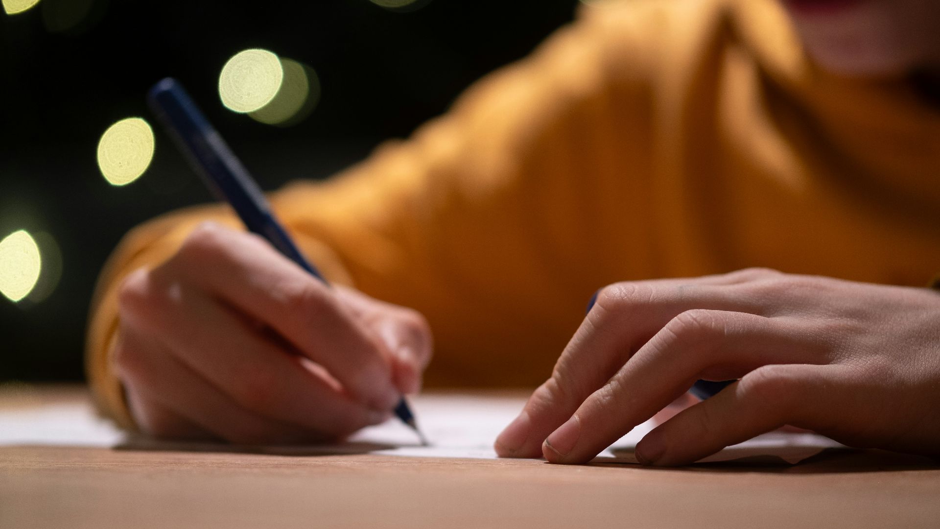 A person writing on a piece of paper with a pen