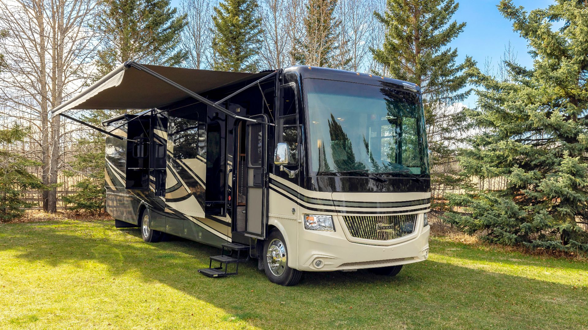a motor home parked in the grass near some trees