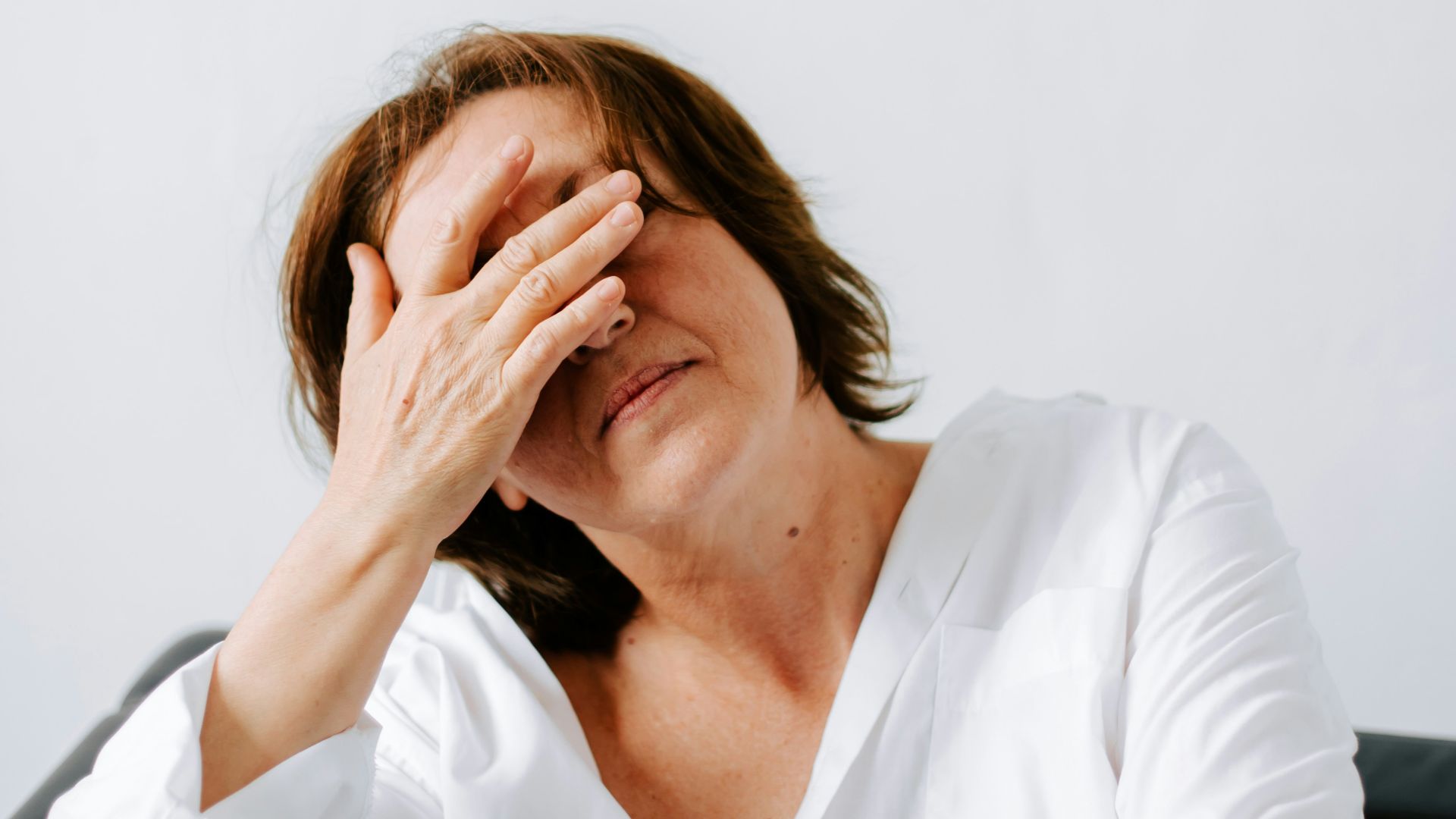 a woman sitting on a couch holding her hands to her face