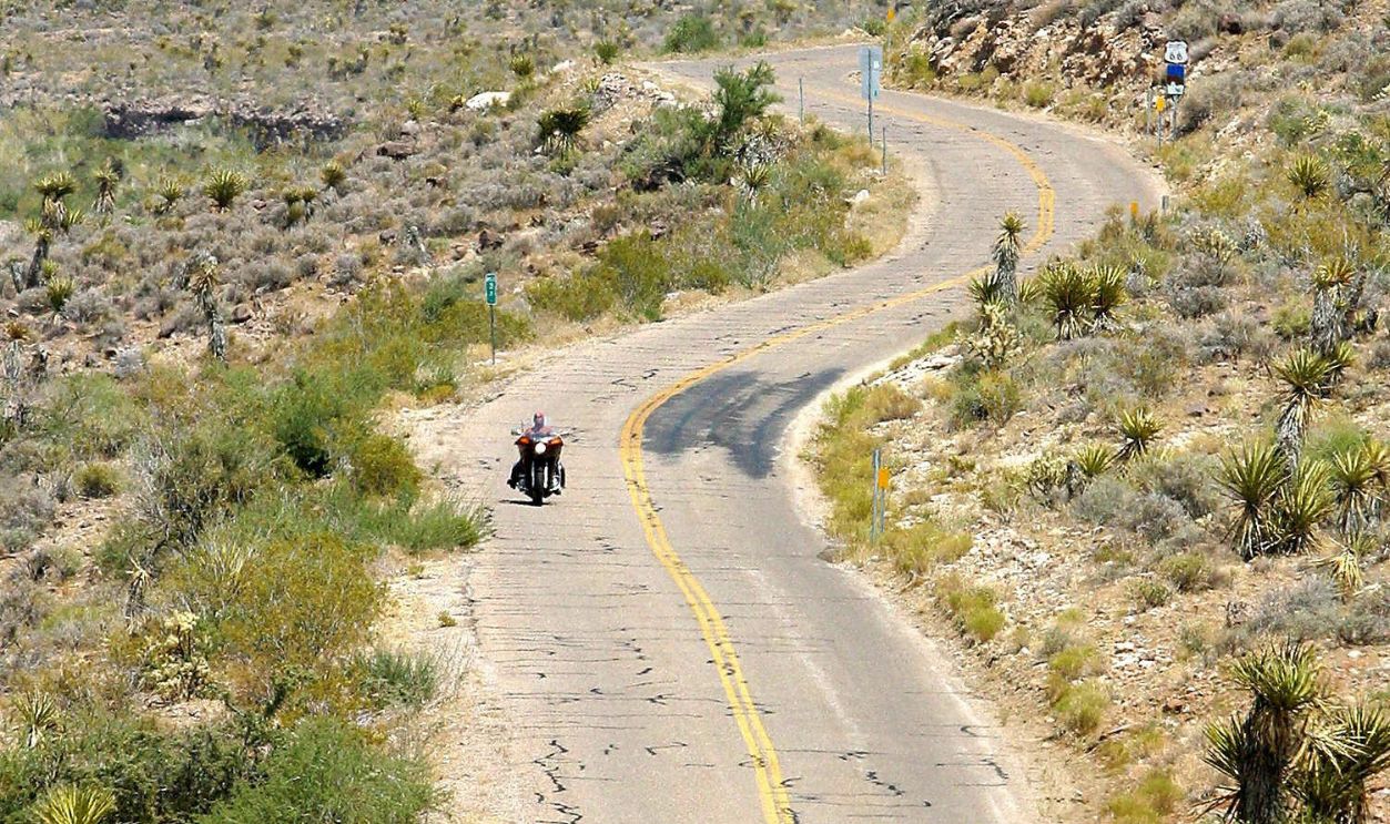 A lone motorcycle rider travels on historic Route 66 across the western Arizona desert on the approach to Oatman, AZ, 12 July 2003. Route 66, 2,448 miles (3,939 km) of two-lane highway, was once the main artery between Chicago to Los Angeles. Between the early 1970's and 1984 the road was slowly bypassed as Interstate 40 was built. Now remaining sections of 66, including this desolate and winding 50-mile stretch from Kingman, AZ to the California border, still serve local traffic and attract motorcycle riders and tourists in search of classic Americana. 