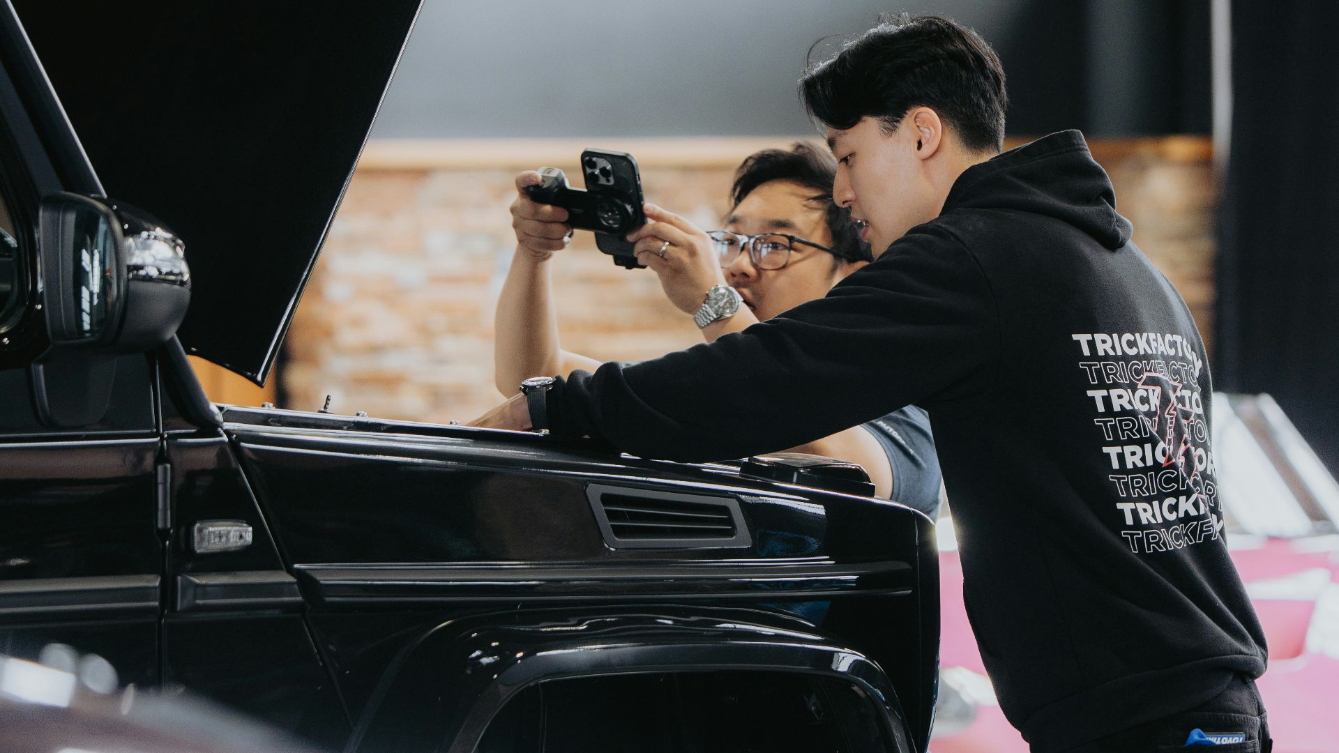 People inspect a car engine at an auto show.