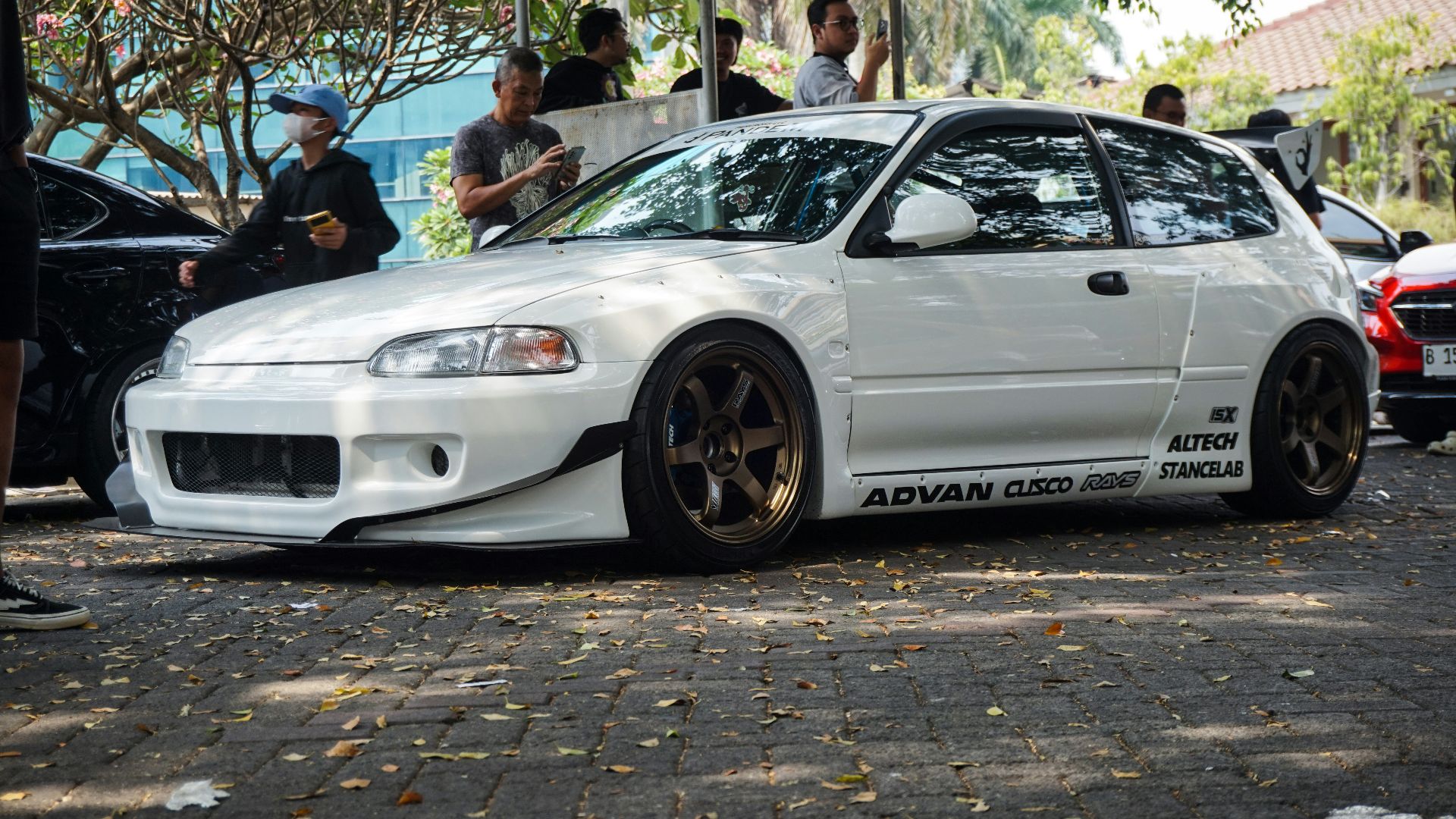 a white car parked in front of a group of people
