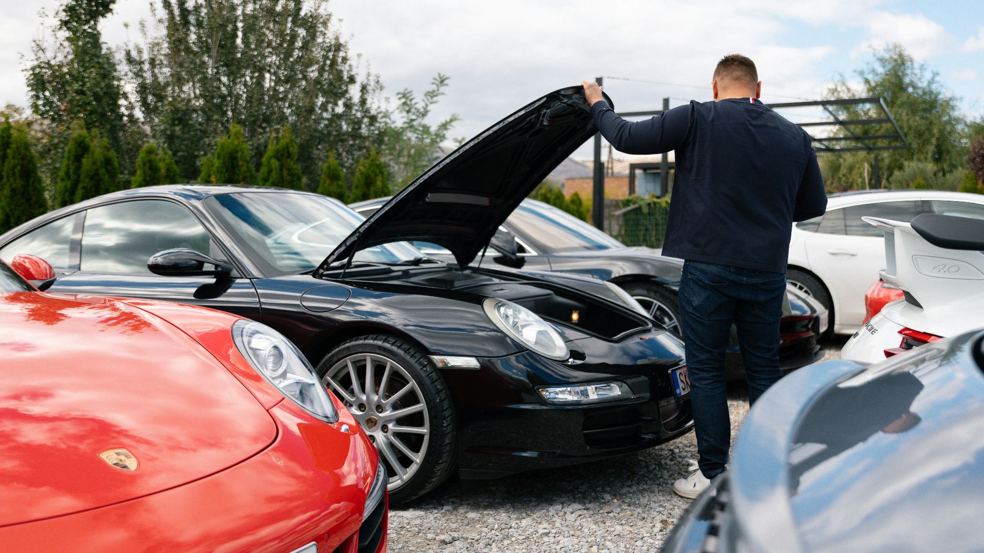 Man opens hood of black sports car